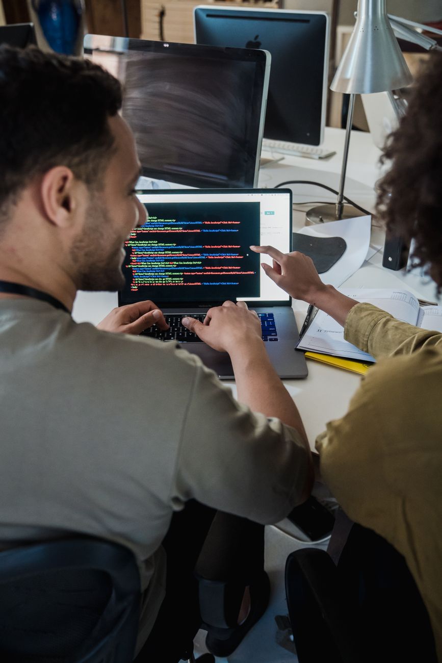Two programmers discussing code on laptop